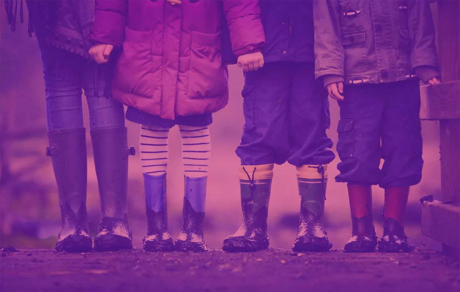 Four children in winter coats and muddy rubber boots